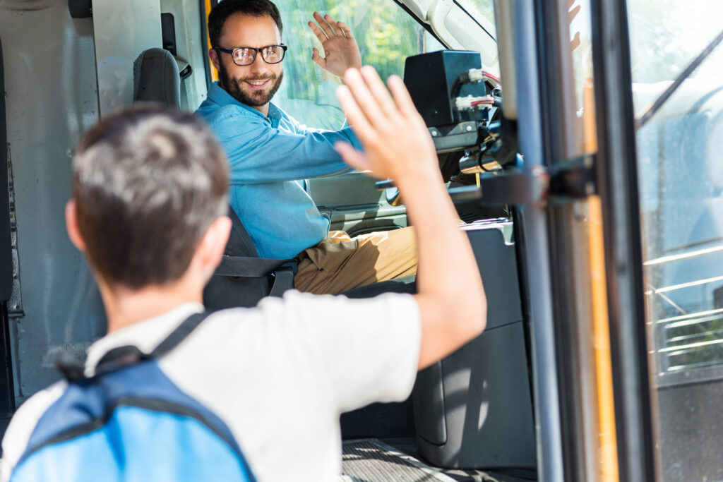 Freundlicher Busfahrer begrüßt neuen Fahrgast mit einem Handgruß.