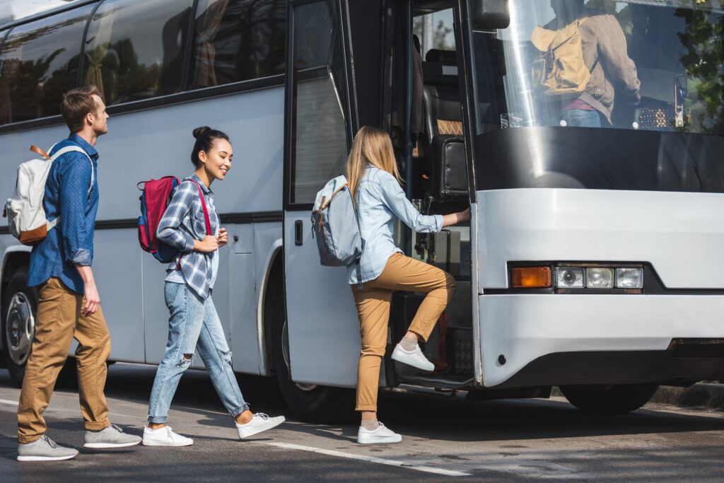 Mehrere Schühler steigen nach einander sonder Haltestelle aus in einen Reisebus ein.