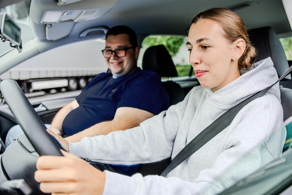 Porträt vom Fahrlehrer und Fahrschülerin bei eine Fahrstunde.
