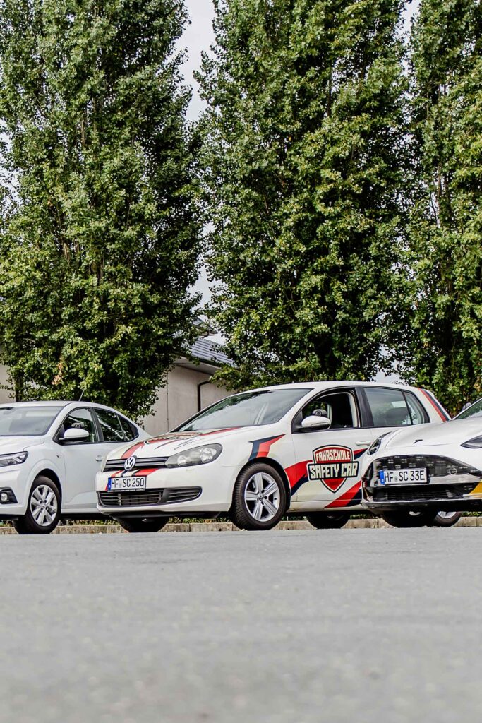 Drei Fahrschule-Autos die nebeneinander stehen.