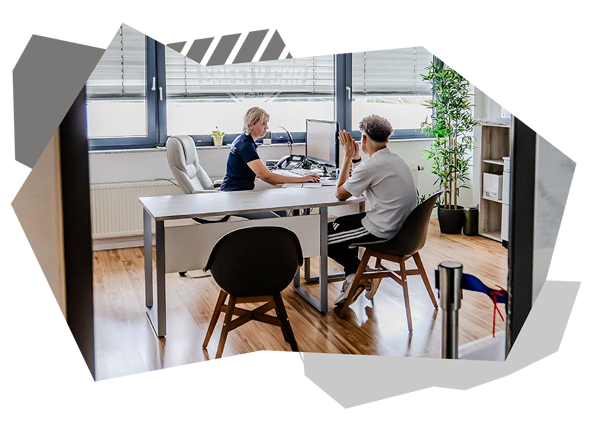 Fahrschulmitarbeiterin und Fahrschüler führen ein Gespräch im Büro der Fahrschule.