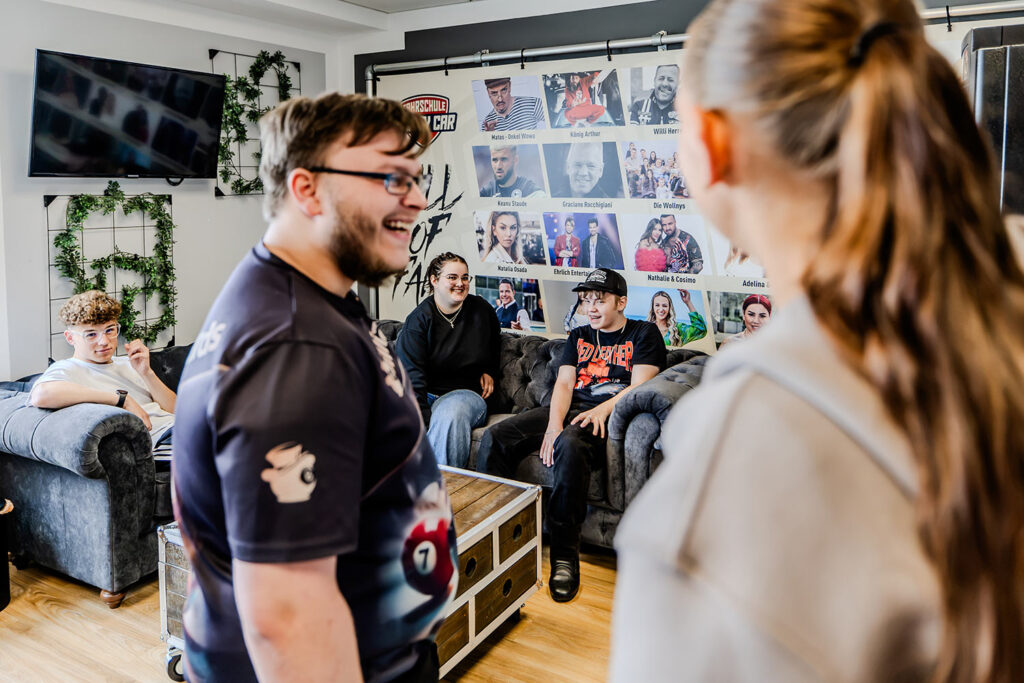 Mehrere Fahrschüler und Fahrschülerinnen unterhalten sich gemeinsam in der Lounge des Eingangsbereich der Fahrschule.