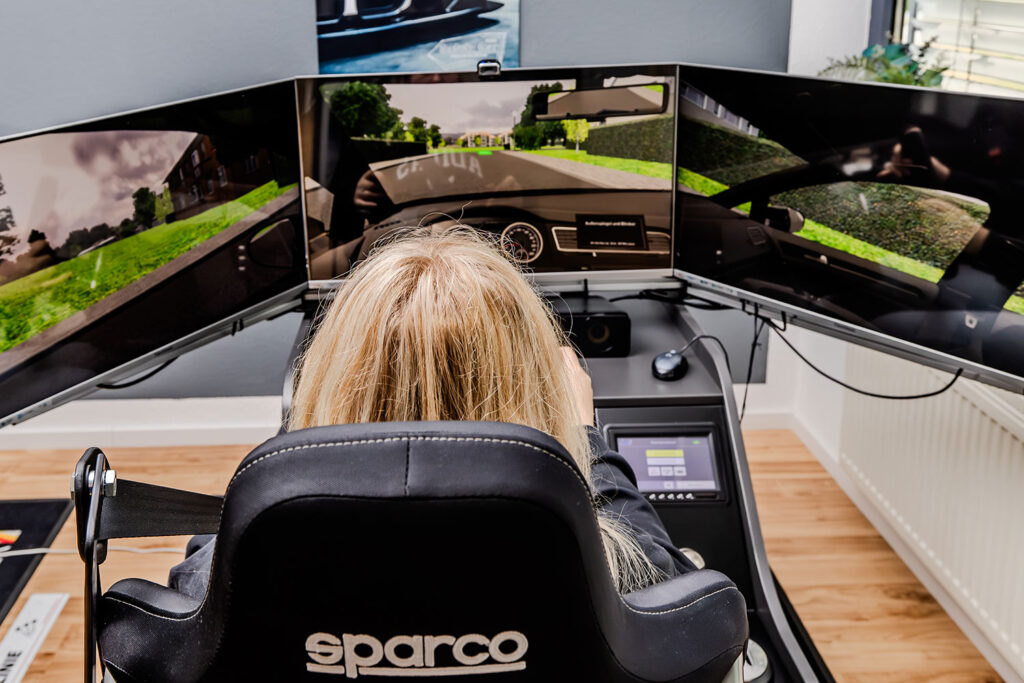 Eine Fahrschülerin macht gerade eine Praxis-Fahrstunde auf einem Fahrsimulator.