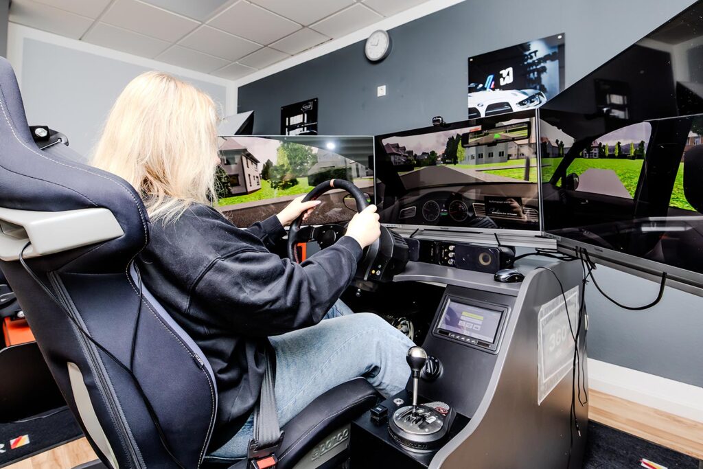 Eine Fahrschülerin sitzt an einem Fahrsimulator und macht ihre Praktische Fahrstunde dort.